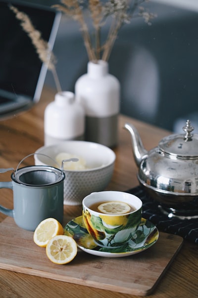 茶几上放满茶和柠檬的杯子旁边的灰色茶壶